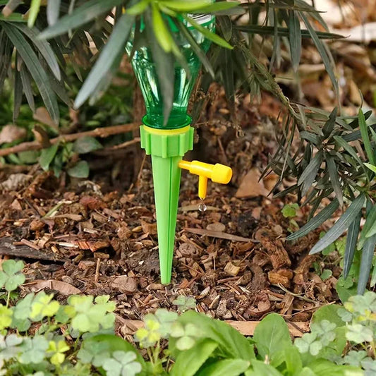 Green garden watering device with yellow valve attached to a plant