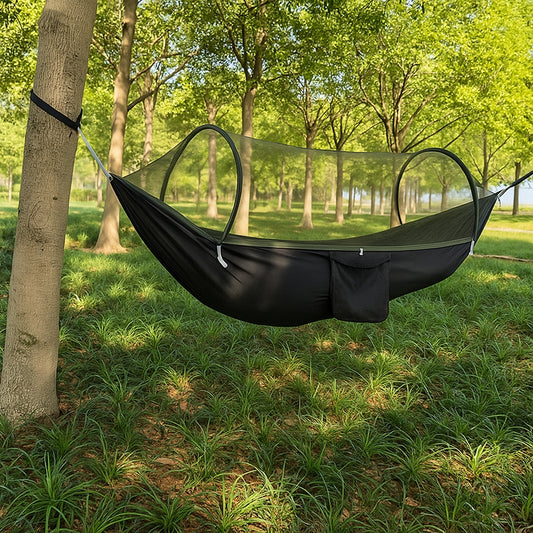 Black hammock with mosquito net hanging between two trees in a park.