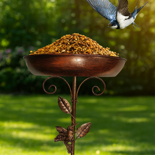 Decorative bird feeder with seeds on a stand in a garden setting