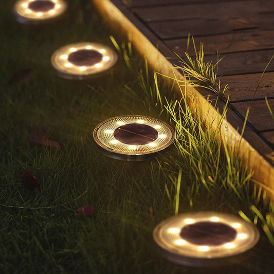 Solar-powered outdoor lights embedded in grass next to a wooden deck