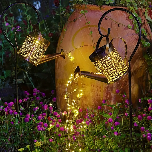 Decorative solar lights shaped like watering cans with fairy lights in a garden setting.