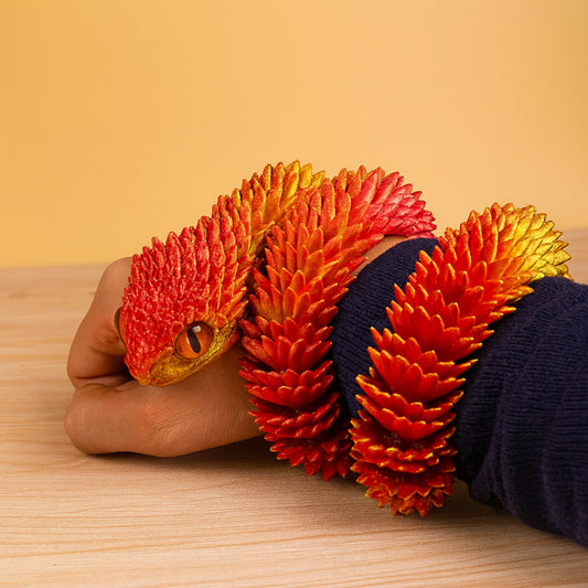 Person holding a colorful dragon-shaped stress ball on a wooden surface with a yellow background
