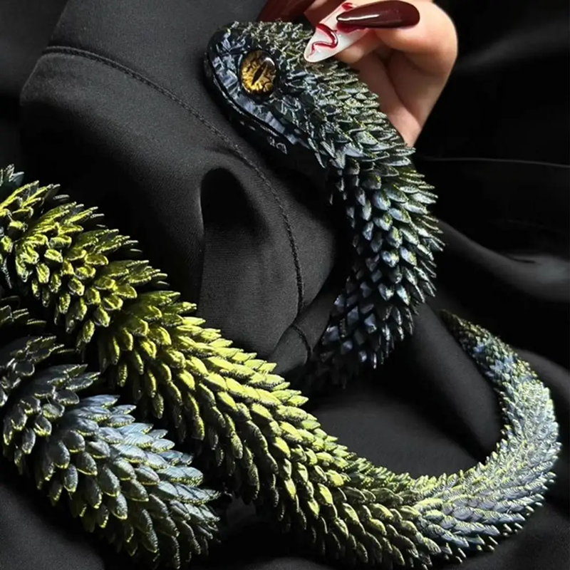 Green snake-like creature held by a person with dark nail polish against a black background