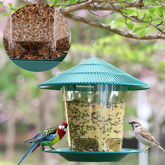 Green bird feeder with birds perched on it, surrounded by greenery.