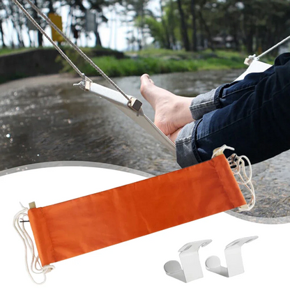 Person relaxing in a hammock with an orange pad over their feet, by a river.