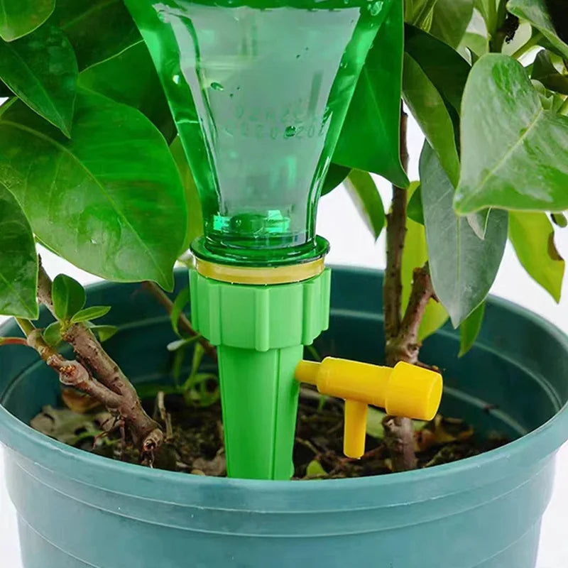 Green and yellow plant watering device in a pot with green leaves.