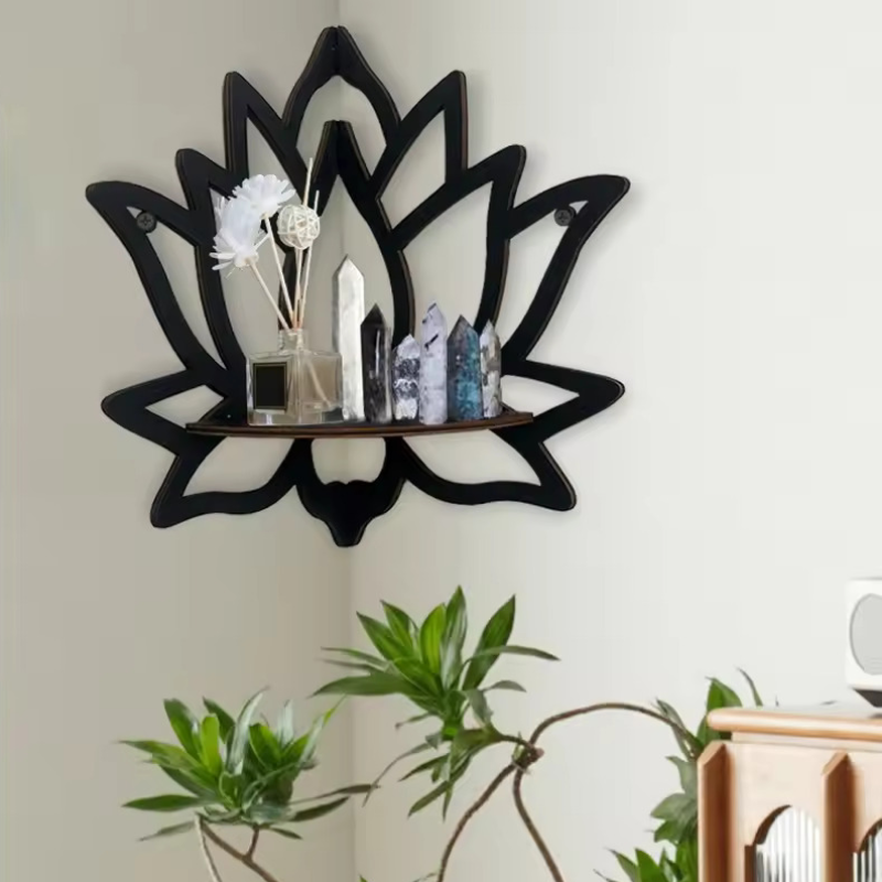 Black lotus-shaped wall shelf with decorative items against a light wall.