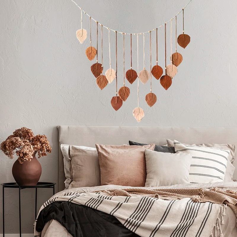Decorative leaf garland hanging above a bed with pillows and a blanket.
