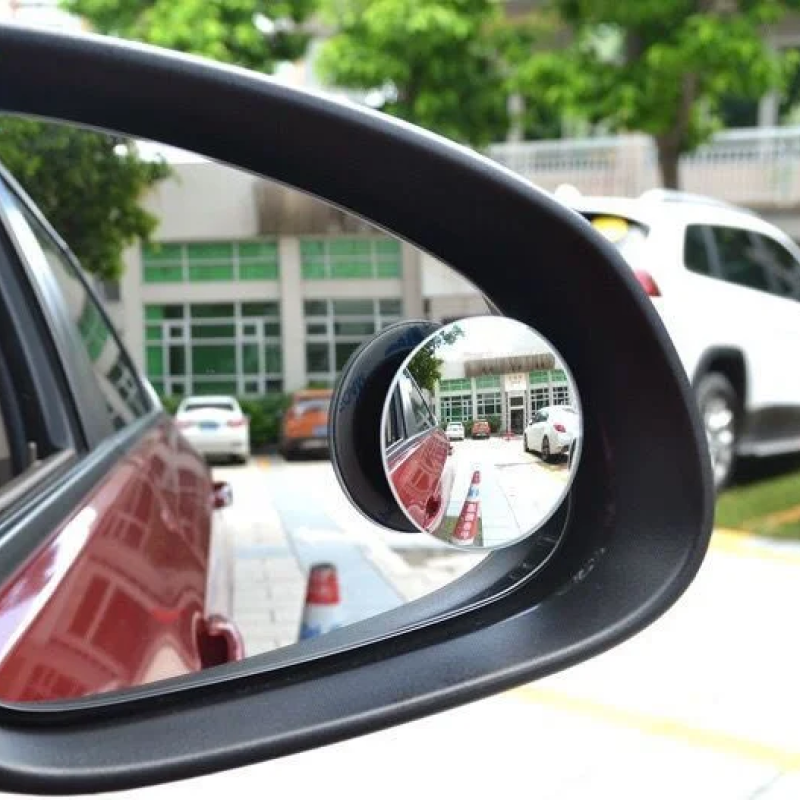 Car side mirror with a blind spot mirror attached, showing additional vehicles in the reflection.