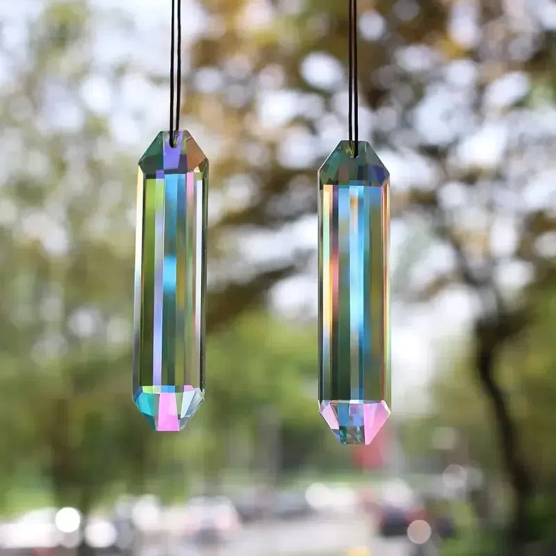 Two colorful crystal prisms hanging against a blurred natural background