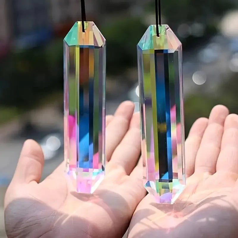 Two crystal prisms held in hands with a blurred outdoor background