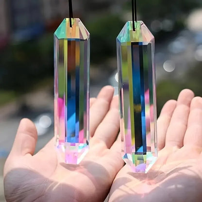Two crystal prisms held in hands with a blurred outdoor background