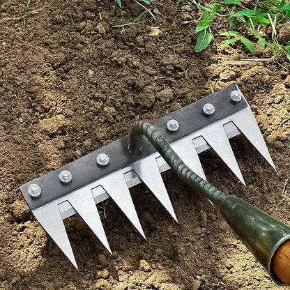 Garden tool with metal spikes on a soil background