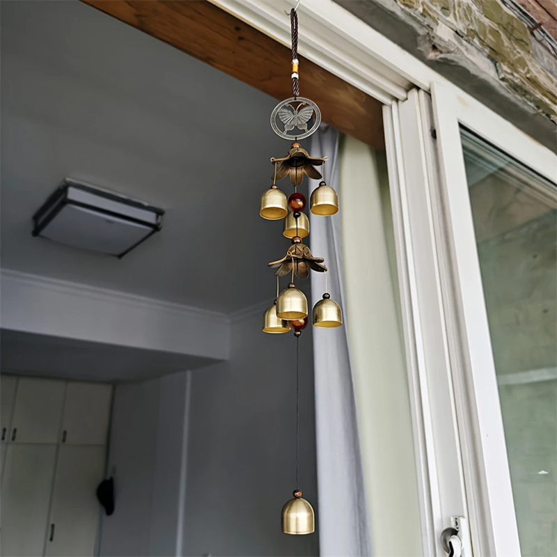 Decorative hanging lantern with gold bells near a window indoors