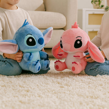 Two children holding blue and pink plush toys on a carpeted floor.
