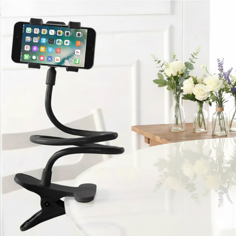 Black phone holder with a smartphone on a white surface with flowers in the background