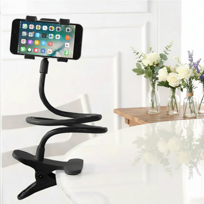 Black phone holder with a smartphone on a white surface with flowers in the background