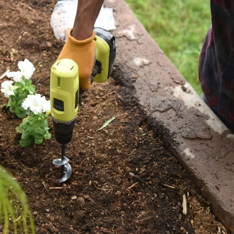 Person using a drill to plant flowers in garden soil