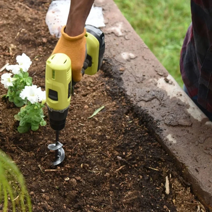 Person using a drill to plant flowers in garden soil