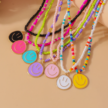 Colorful beaded necklaces with smiley face pendants on a beige background