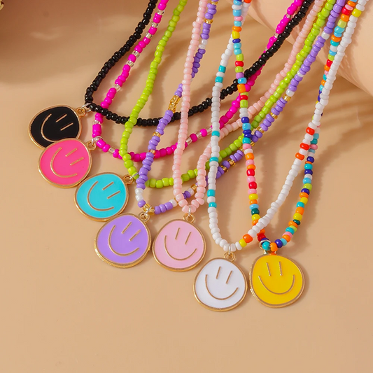 Colorful beaded necklaces with smiley face pendants on a beige background