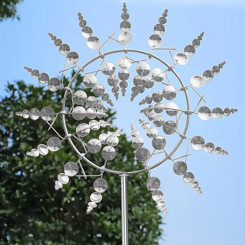Decorative metal wind spinner with clear spherical elements against a blue sky.