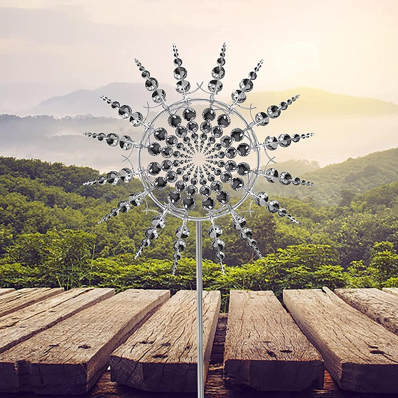 Decorative metal sun sculpture on a wooden surface with a scenic background of trees and mountains.