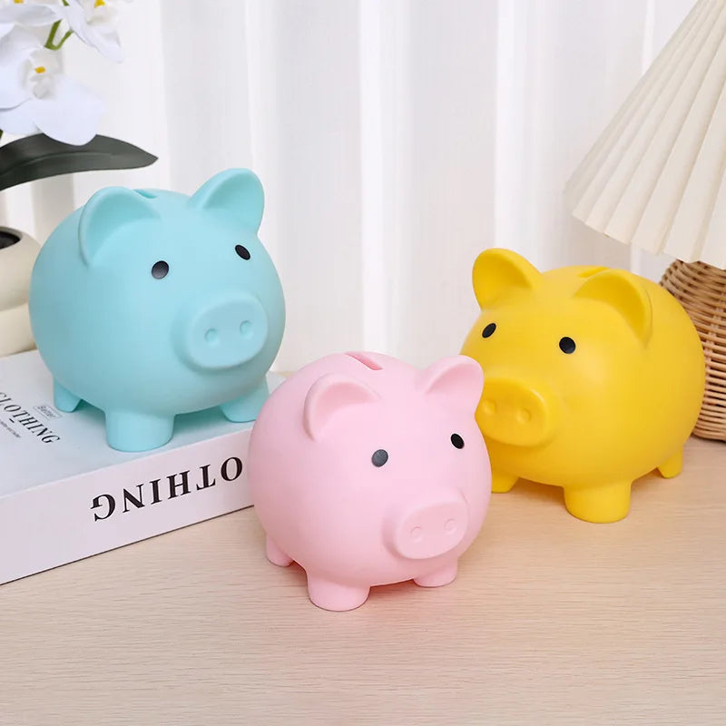 Three colorful piggy banks (blue, pink, yellow) on a surface with a blurred background.