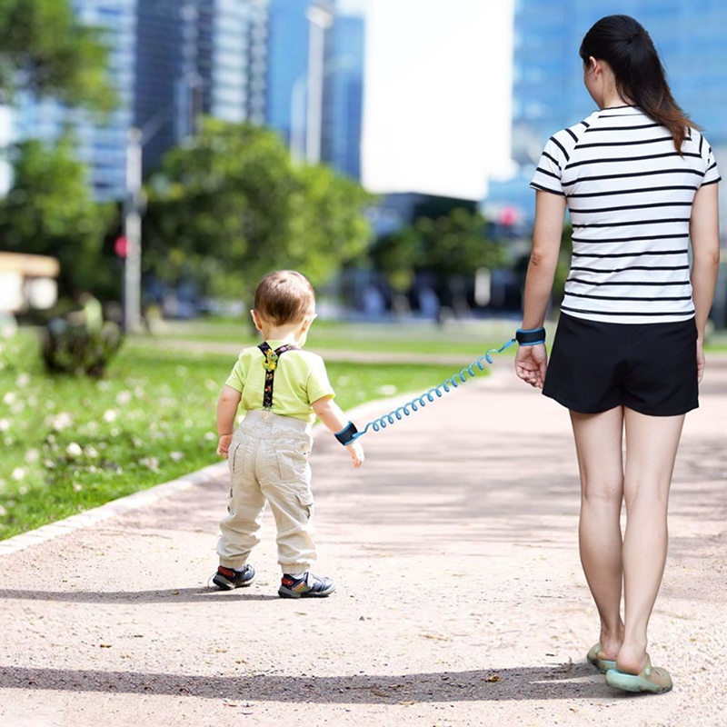 Woman and child walking on a path with a leash in an urban park setting