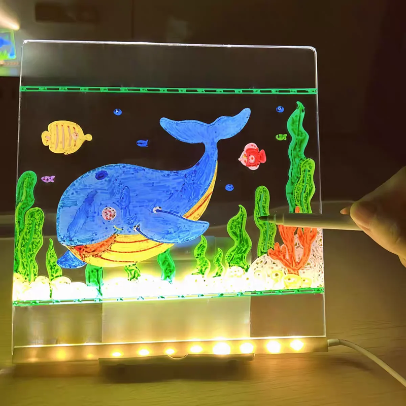 Light-up drawing board with whale illustration and hand holding a pen.