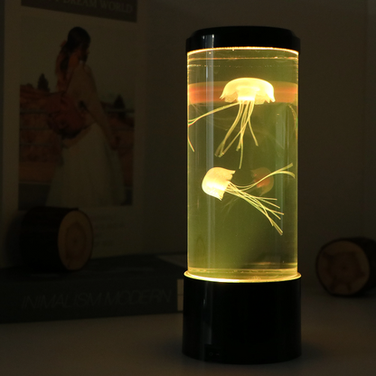 Glass container with jellyfish on a black base in a dimly lit room.