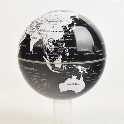 Black and white world globe on a stand with a light gray background