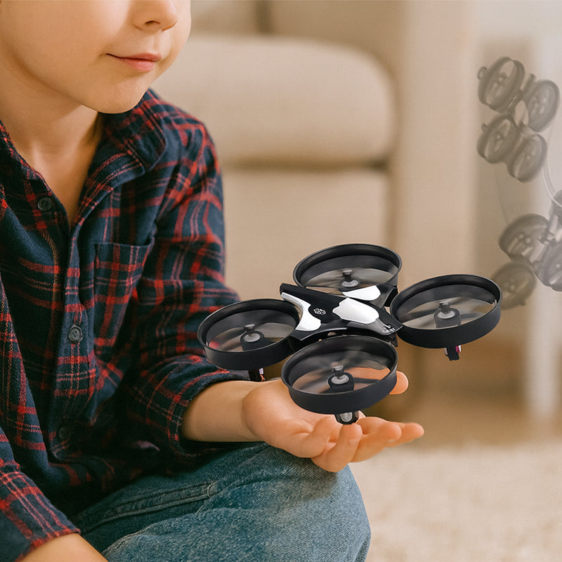 Child holding a small black drone in their hands with a blurred background