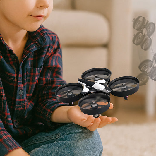 Child holding a small black drone in their hands with a blurred background
