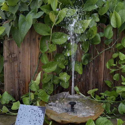 Small water fountain surrounded by green foliage with a wooden background