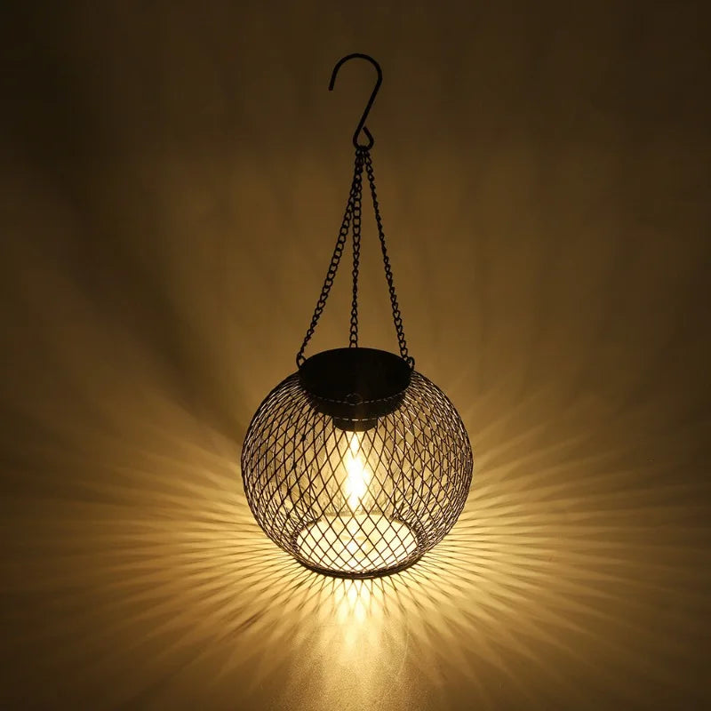 Wire mesh hanging light fixture casting a warm glow on a dark background