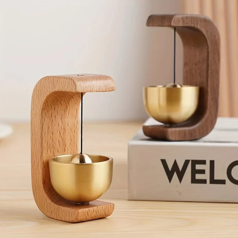 Wooden and gold balance toy on a wooden surface with 'WELCOME' box in the background
