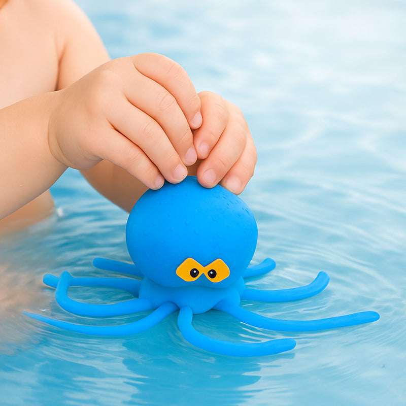 Child's hand holding a blue octopus toy in water