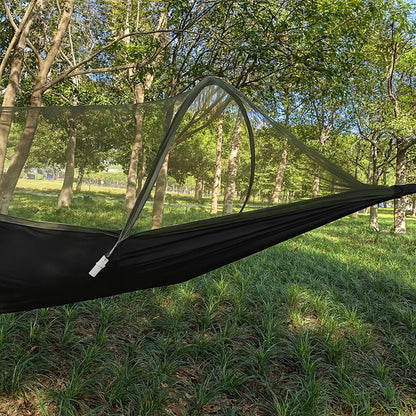 Black hammock with mesh canopy in a forest setting