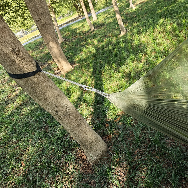 Green hammock attached to trees in a grassy outdoor setting
