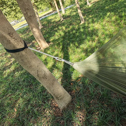 Green hammock attached to trees in a grassy outdoor setting