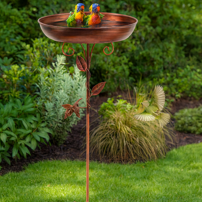 Decorative copper bird bath with birds on a garden background