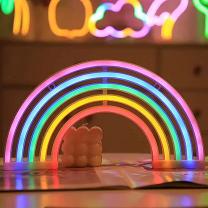 Neon rainbow light with a cloud-shaped object underneath on a reflective surface.