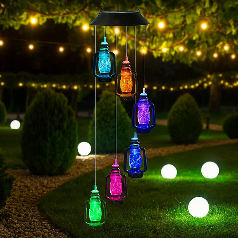 Colorful solar-powered hanging lights in a garden setting with string lights in the background.