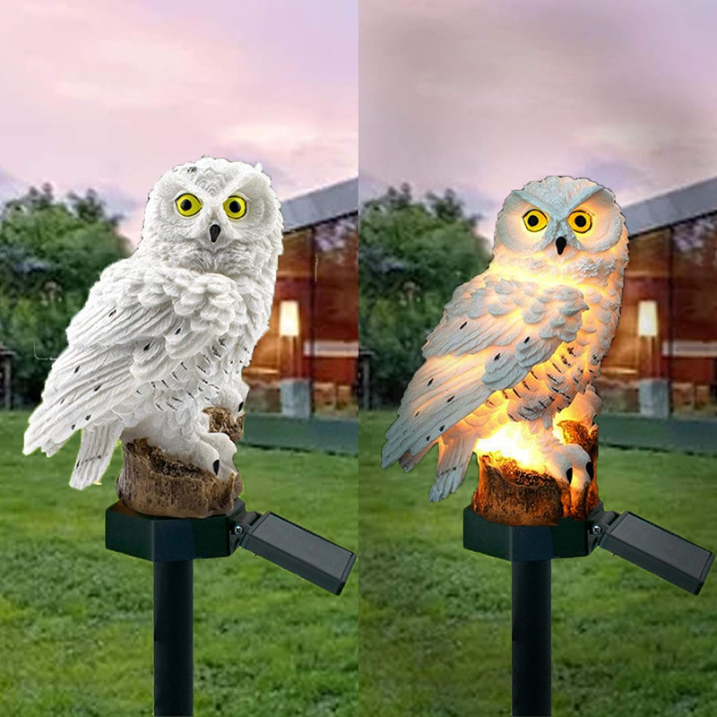 Solar-powered owl light on a grassy area with a house in the background