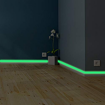 Room corner with green LED strip lights on a wooden floor and dark walls.