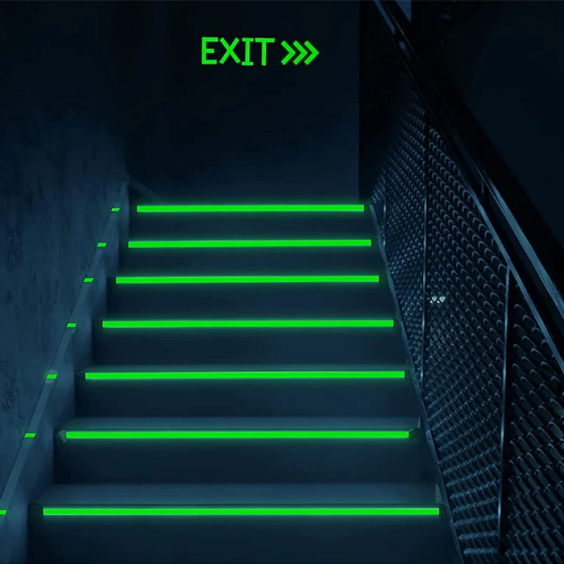 Staircase with green exit signs on a dark background
