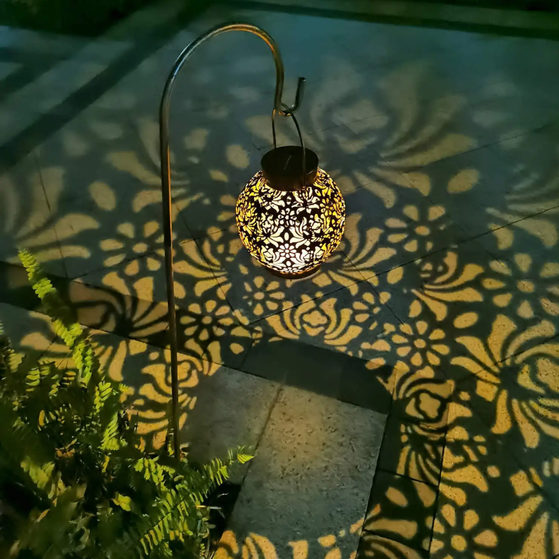 Decorative lantern casting intricate shadows on a tiled floor with plants nearby