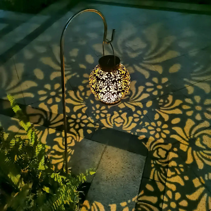 Decorative lantern casting intricate shadows on a tiled floor with plants nearby
