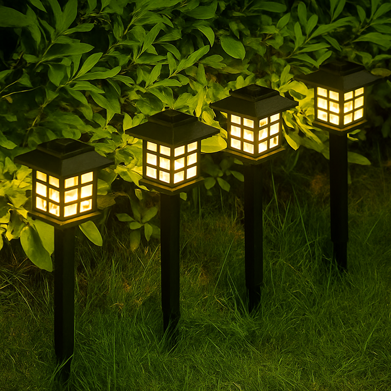 Set of four solar garden lights embedded in grass with a green leafy background